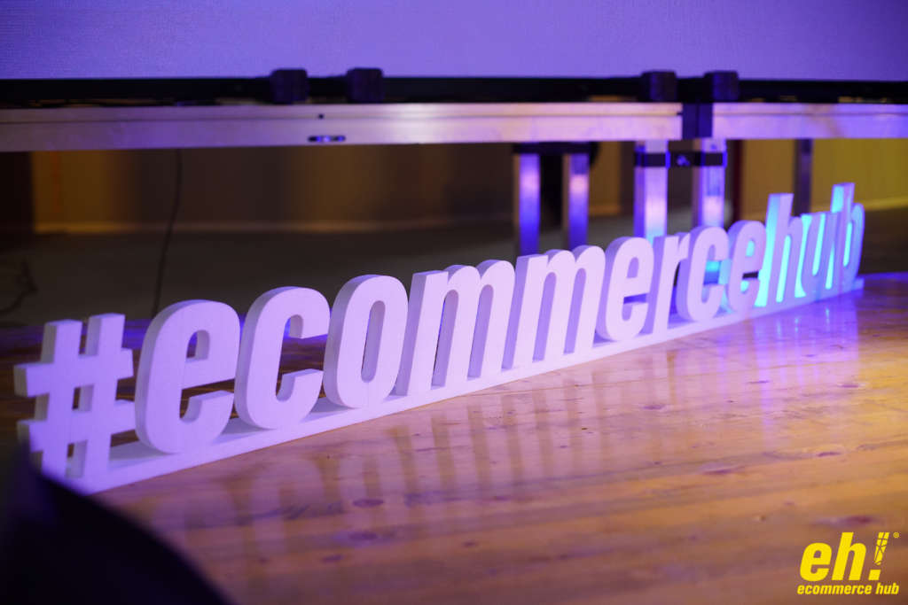 L'immagine mostra la scritta ecommercehub preceduta dal cancelletto, tipico utilizzo dell'hashtag. La scritta è posizionata su un parquet.